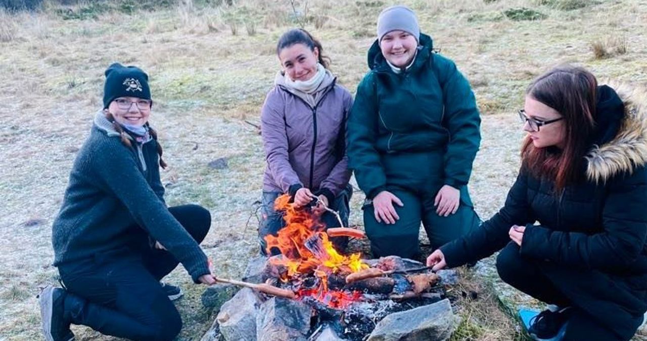 Elever griller pølser på bål